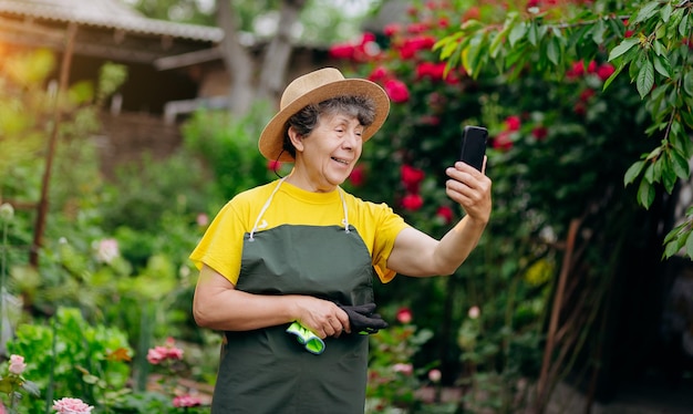 Senior femme jardinier dans un chapeau travaillant dans sa cour et parle au téléphone Le concept de jardinage de plus en plus et de prendre soin des fleurs et des plantes