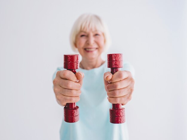 Senior femme joyeuse faisant du sport avec des haltères Anti-âge sports style de vie sain