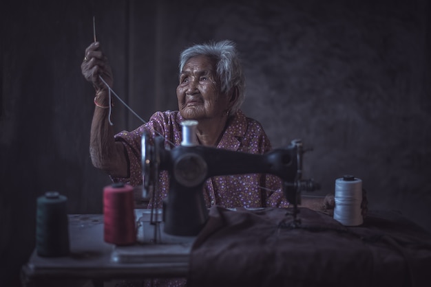 Senior femme mignonne âgée de 90 ans à l&#39;aide d&#39;une machine à coudre vintage.