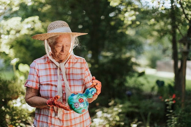 Senior femme raccrochant une maison d&#39;oiseau coloré