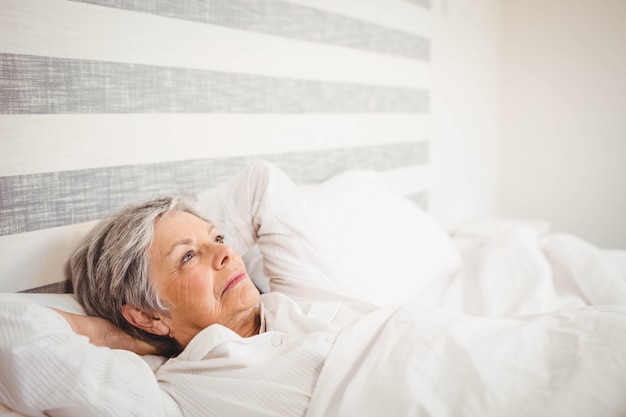 Senior femme réfléchie se détendre sur le lit