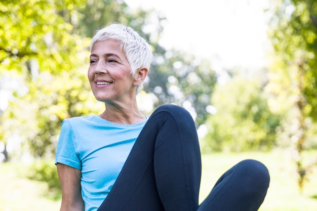 Senior femme resing après une séance d&#39;entraînement dans un parc