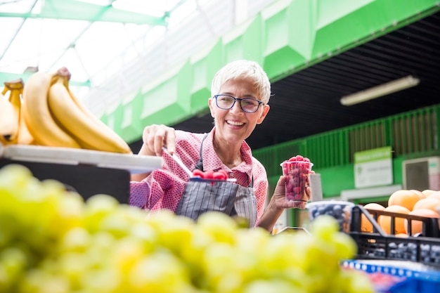 Senior femme vend des framboises sur le marché