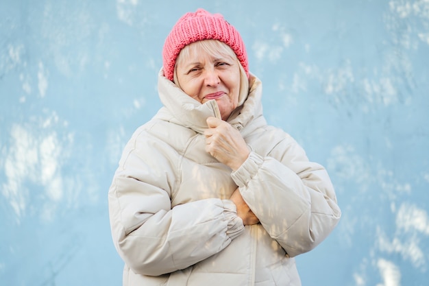 Senior femme en vêtements d'extérieur à la mode. Femme âgée au chapeau rose tricoté souriant