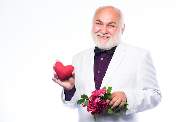 Senior gentleman âme romantique L'homme tient le symbole du cœur de l'amour Romance et rencontres Services de rencontres pour les personnes âgées Concept de gentleman Vrai gentleman Bel homme barbu bien entretenu portant un smoking