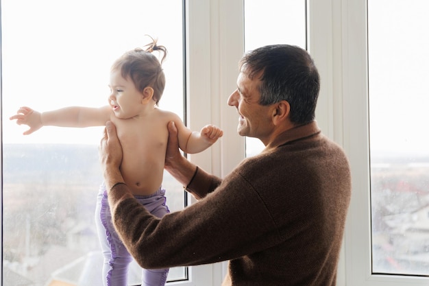 Senior homme âgé jouant à son bébé petite-fille le tenant dans l'air deux générations d'âge fami