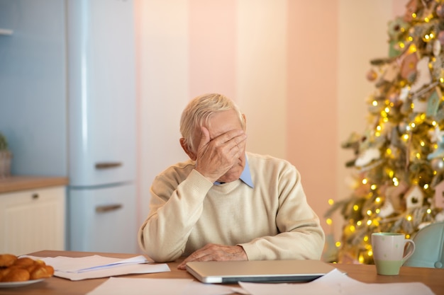 senior homme assis à la table et travaillant sur un ordinateur portable