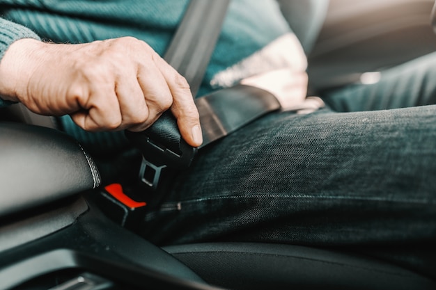 Senior Homme Attacher La Ceinture De Sécurité Tout En étant Assis Dans Sa Voiture.