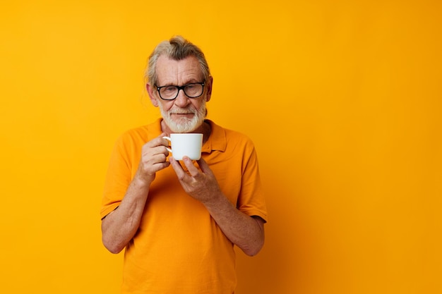 Senior homme aux cheveux gris dans un t-shirt jaune tasse blanche fond isolé