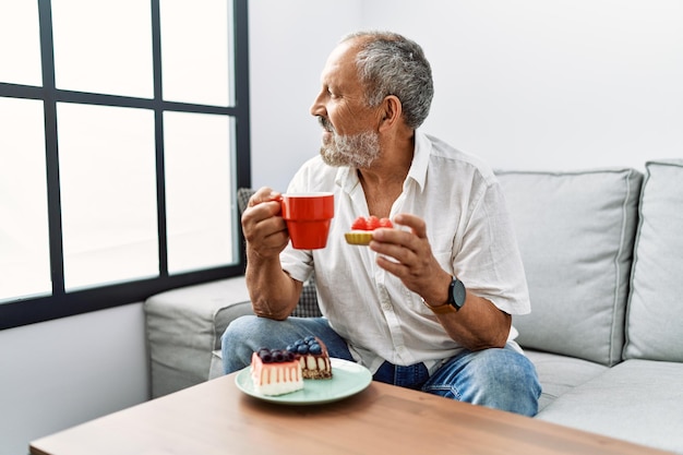 Senior homme aux cheveux gris souriant confiant prenant son petit déjeuner à la maison