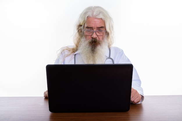 Senior homme barbu médecin portant des lunettes tout en utilisant un ordinateur portable