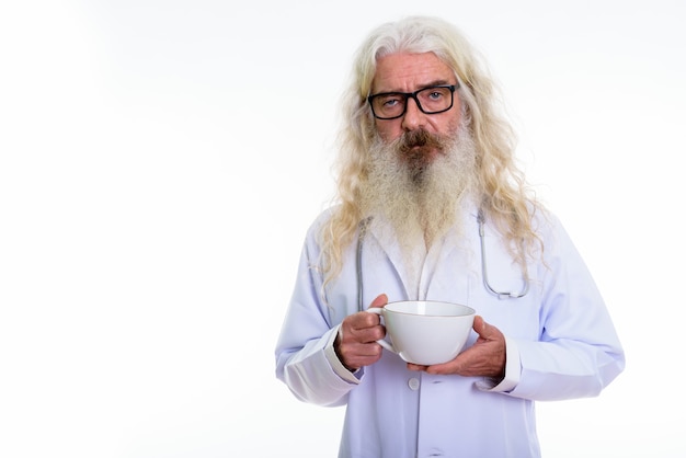 Senior homme barbu médecin tenant une tasse de café