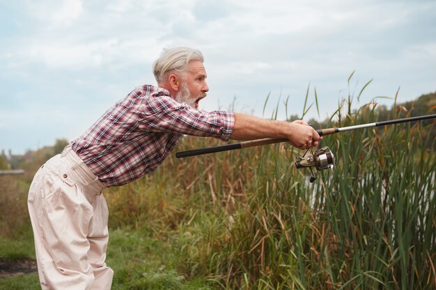 Senior homme barbu pêchant sur un lac