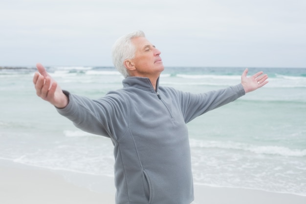 Senior homme avec les bras tendus à la plage