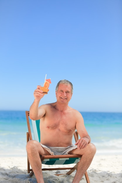 Senior homme buvant un cocktail sur la plage