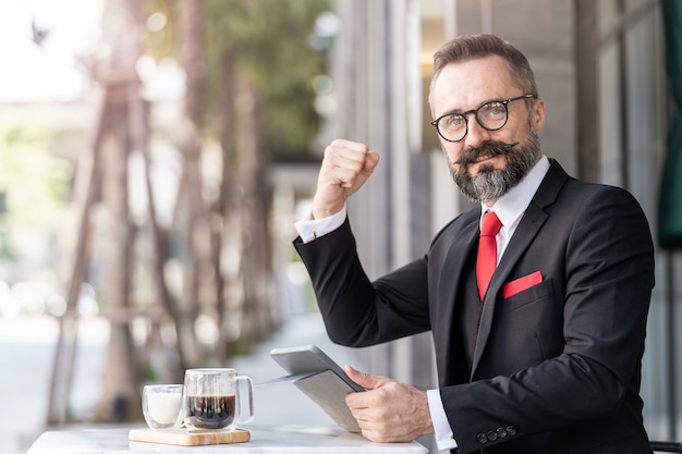 Senior homme en costume d'affaires intelligent pensant et assis dans une table basse en plein air.