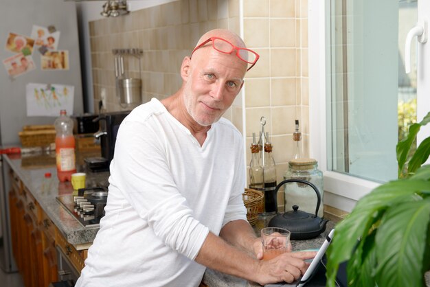 Senior homme dans la cuisine à l'aide de tablette numérique