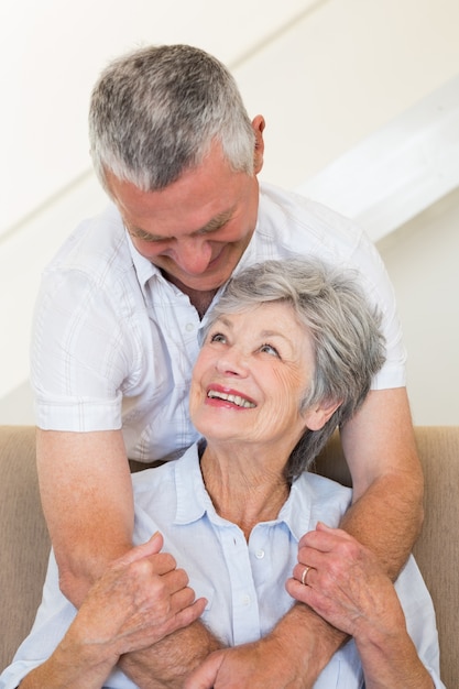 Senior homme embrassant la femme assise sur le canapé