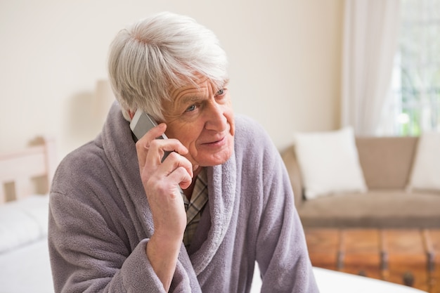 Senior homme faisant un appel téléphonique sur le lit