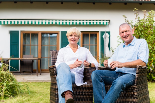 Senior homme et femme assis devant la maison