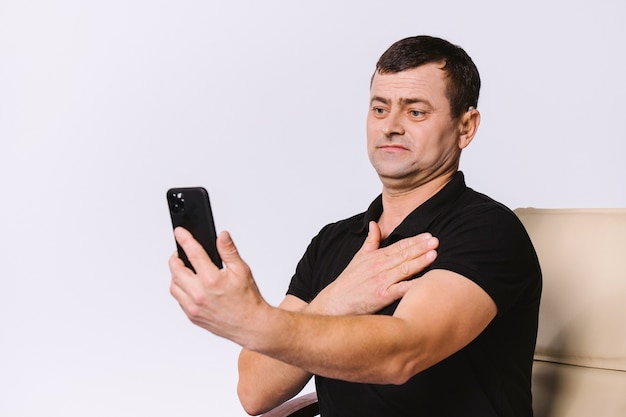 Senior homme malentendant communique par appel vidéo à l'aide de gestes non verbaux. Fond blanc.