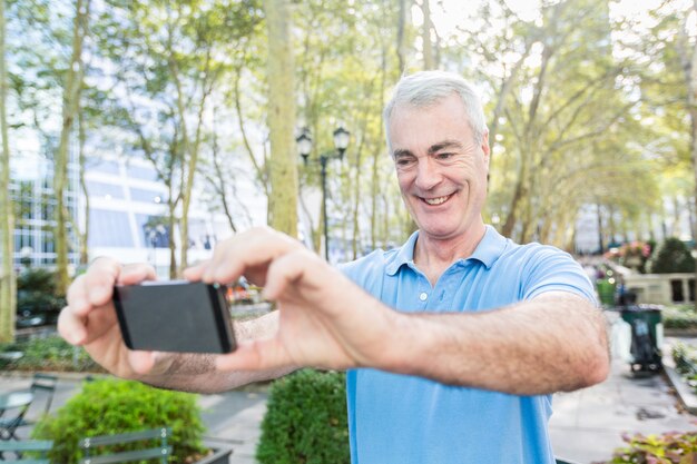 Senior homme prenant un selfie au parc