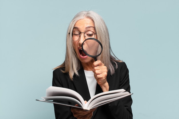 Senior jolie femme avec un livre et une loupe.