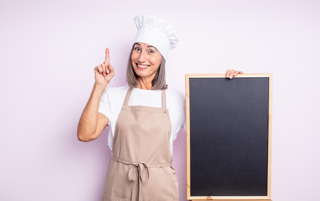 Senior jolie femme se sentant comme un génie heureux et excité après avoir réalisé une idée. concept de chef et tableau noir