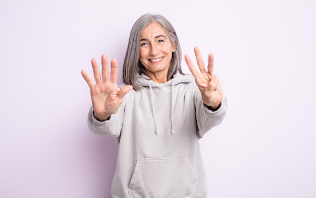 Senior jolie femme souriante et sympathique, montrant le numéro huit ou huitième avec la main vers l'avant, compte à rebours