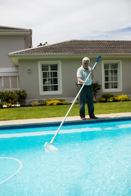 Senior man cleaning piscine sur une journée ensoleillée