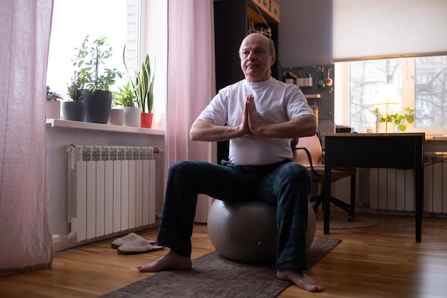 Senior man doing yoga pose ou pilates à la maison