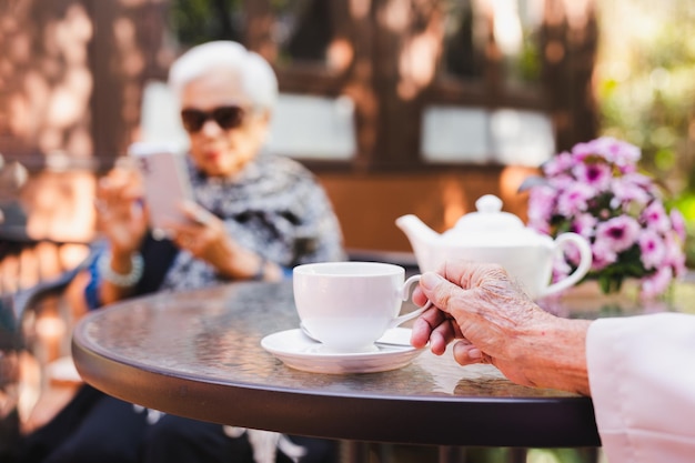 Senior man main tenant une tasse de thé avec sa femme en arrière-plan