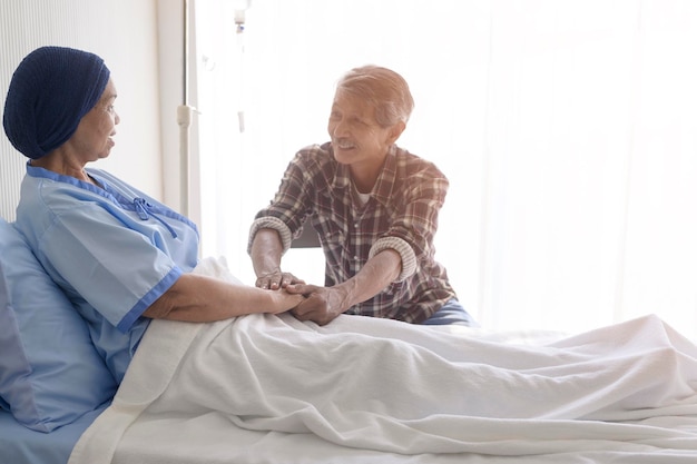 A Senior man visitant une patiente cancéreuse portant un foulard à l'hôpital