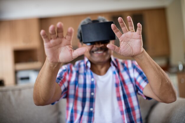 Senior man wearing casque de réalité virtuelle dans le salon