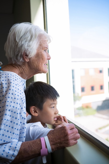 Senior patient et garçon regardant par la fenêtre