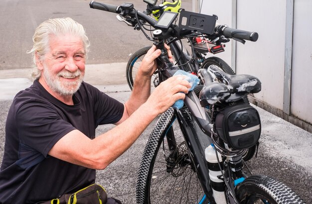 A senior smiling man lave son vélo et s'occupe des détails Station service Pompe haute pression