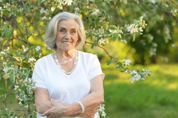 Senior souriante belle femme posant dans le parc du printemps