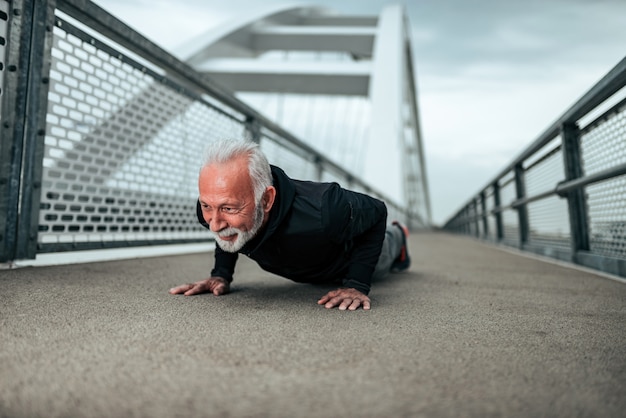 Senior sportif faisant des pompes dans l&#39;environnement de la ville.