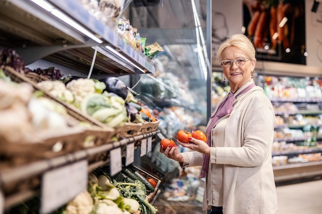 A senior woman acheter des tomates au supermarché