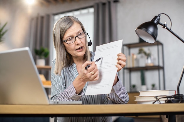 Senior woman chat en ligne avec des collègues de la maison