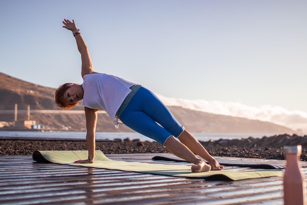 Senior woman doing yoga s'étend au bord de la mer