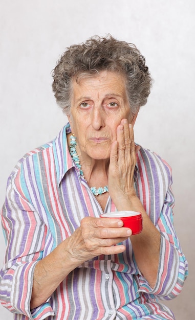 Senior woman entre 70 et 80 ans et une boîte de crème pour le visage