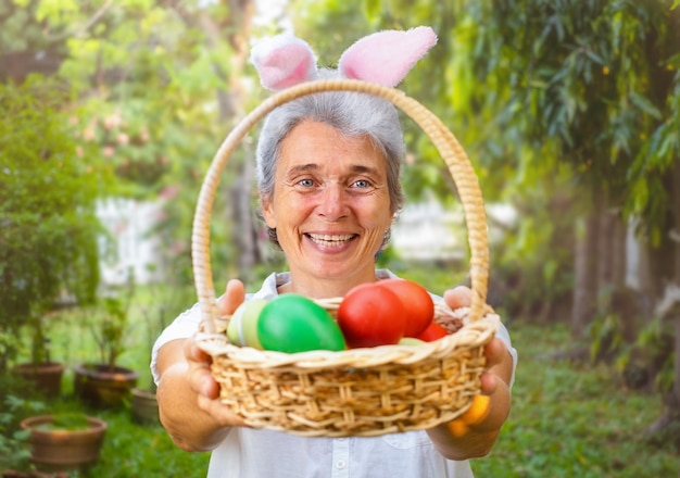 Senior woman holding out panier de Pâques avec des oeufs dans l'arrière-cour