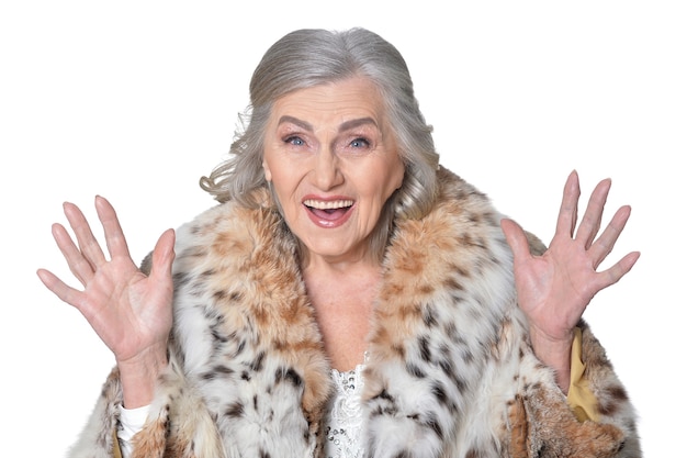 Senior woman in fur haussant la main sur fond blanc