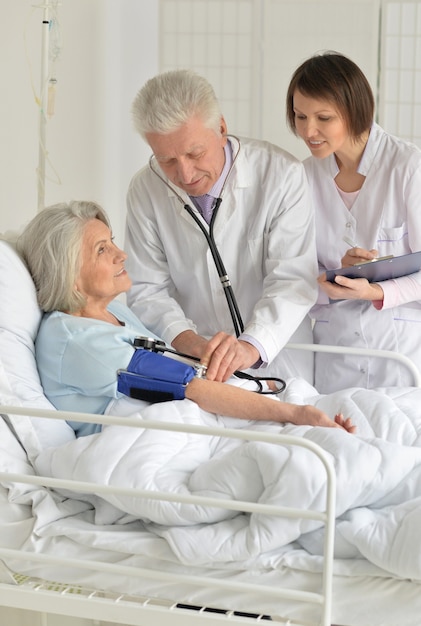 Senior woman in hospital avec des médecins attentionnés