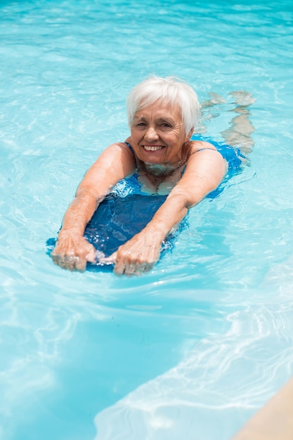 Senior woman nager dans la piscine par une journée ensoleillée