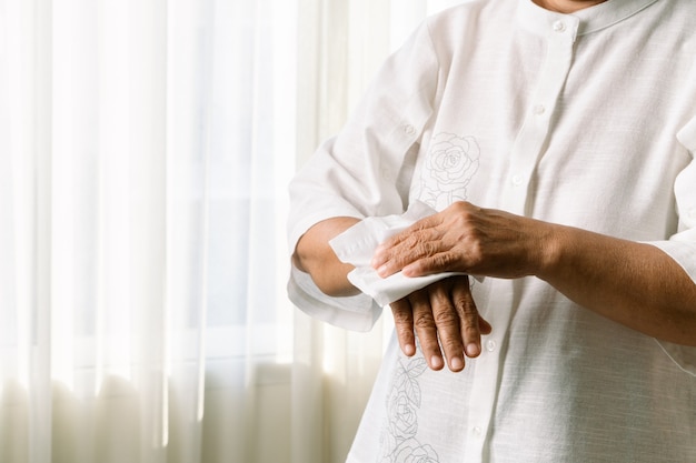 Photo senior woman nettoyant ses mains avec du papier de soie doux blanc. isolé sur fond blanc