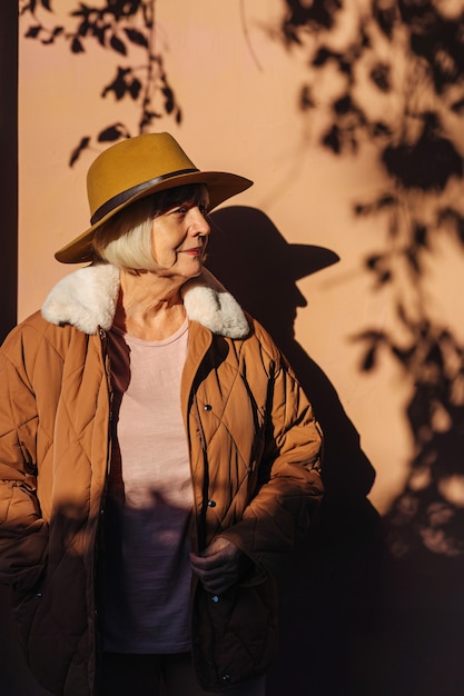 Senior woman reposant dans l'ombre sur la rue. Femme âgée en manteau et chapeau élégant