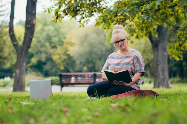 Senior woman reposant dans le parc sur la pelouse