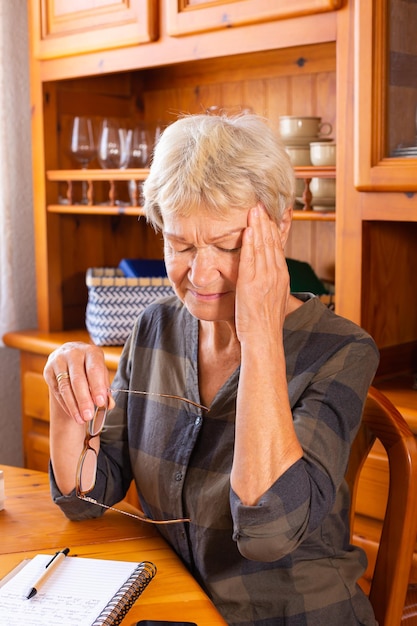 Senior Woman Souffrant De Maux De Tête Tout En Prenant Des Notes